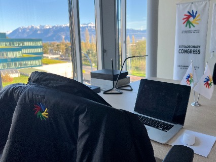 ICSD Office with desk and flag, overlooking scenic French mountains through a tall window.